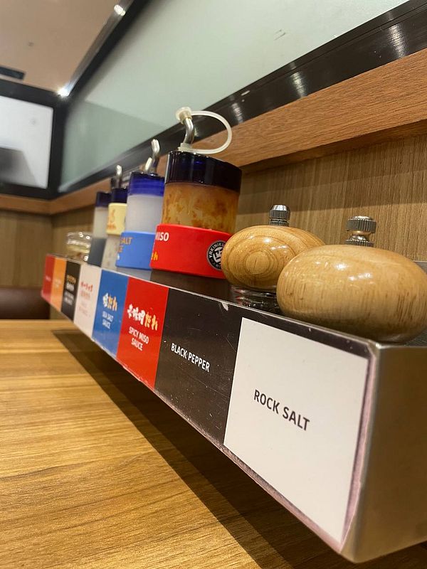 Close-up of grilled meat with chopsticks above a hot grill, ready to be eaten.