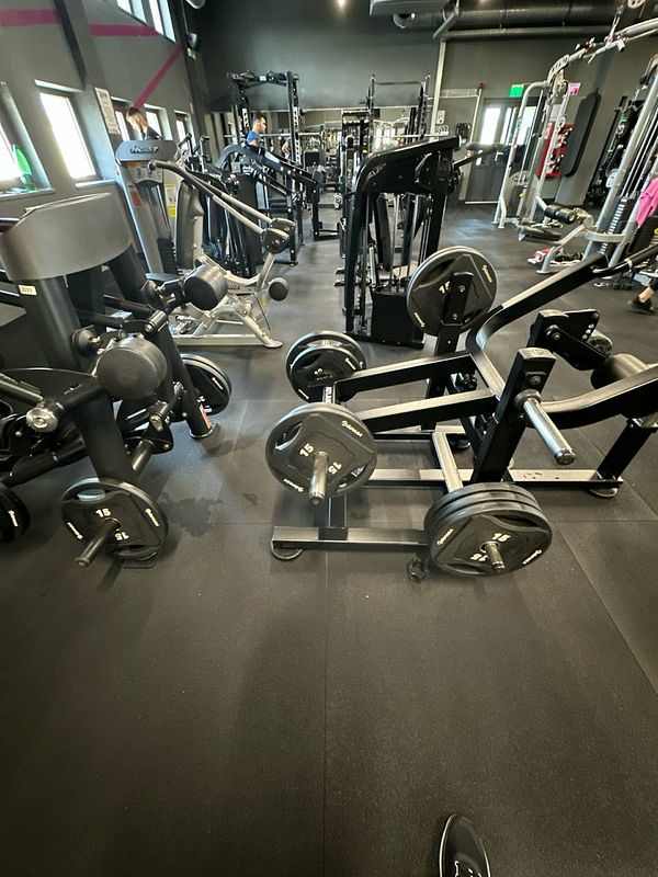 A well-equipped gym space featuring various weightlifting machines and free weights.