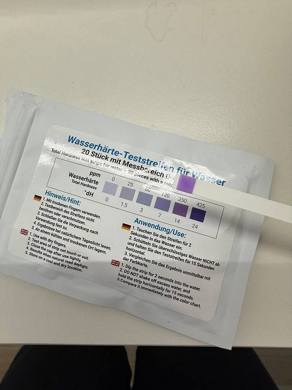 The image displays a water hardness test kit with instructions and a color chart for measuring water hardness levels.