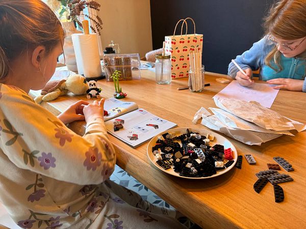 Two children are engaged in creative activities with Lego and drawing on a cozy Christmas morning.