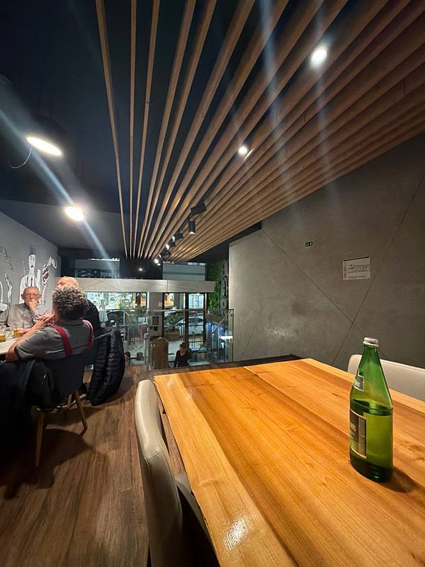 Photograph of a dimly lit restaurant dining area with several tables set and ambient lighting fixtures.