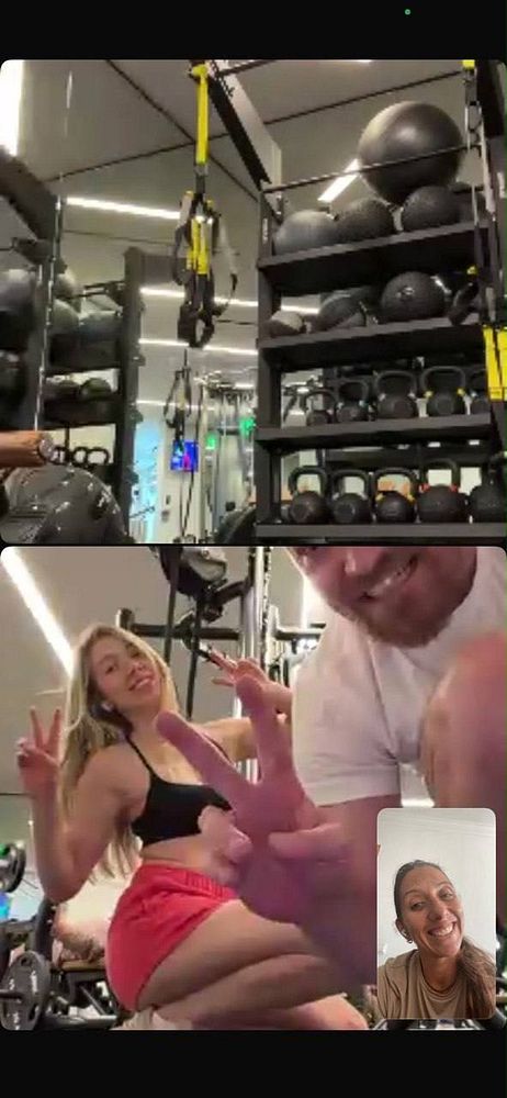 A woman training a man in a gym room with exercise equipment including dumbbells, a bench, and mirrors.