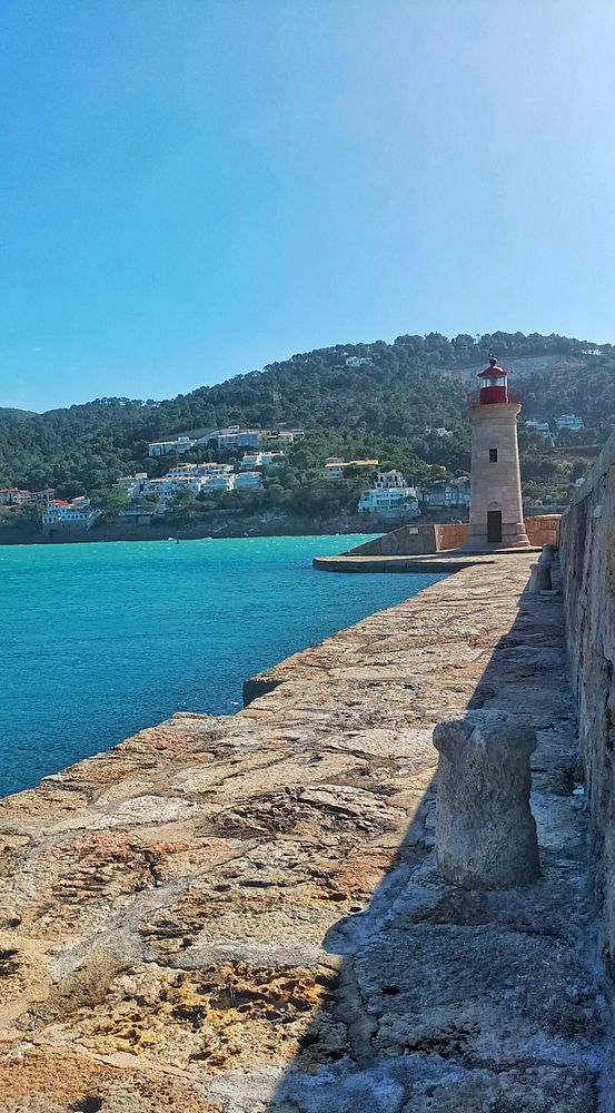 A woman hiking on a rocky landscape with an idyllic view of hills, a lake, and a bright blue sky with clouds.