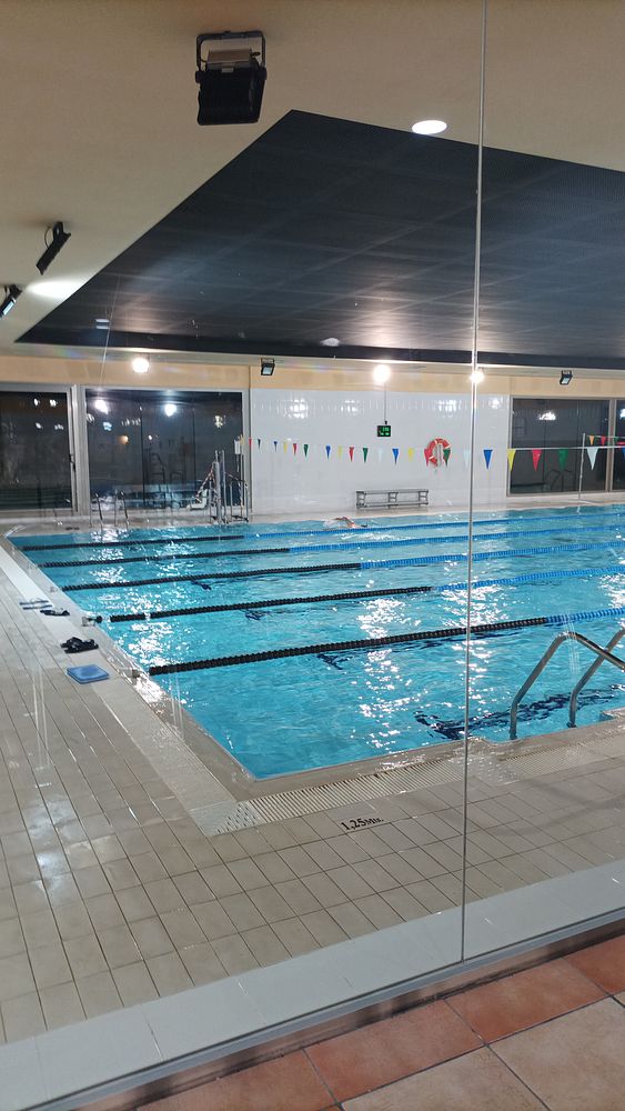 An indoor swimming pool with lanes marked by floating buoys and a lifeguard station.
