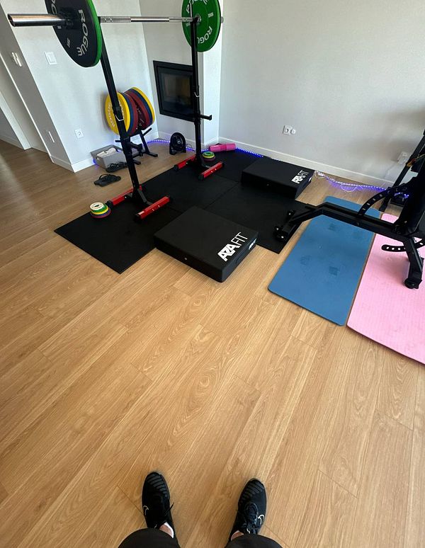 A home gym setup featuring various workout equipment and flooring.