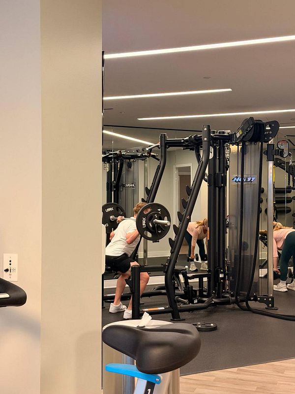 Photograph of a modern gym interior with exercise equipment, benches, and weights arranged throughout the space.