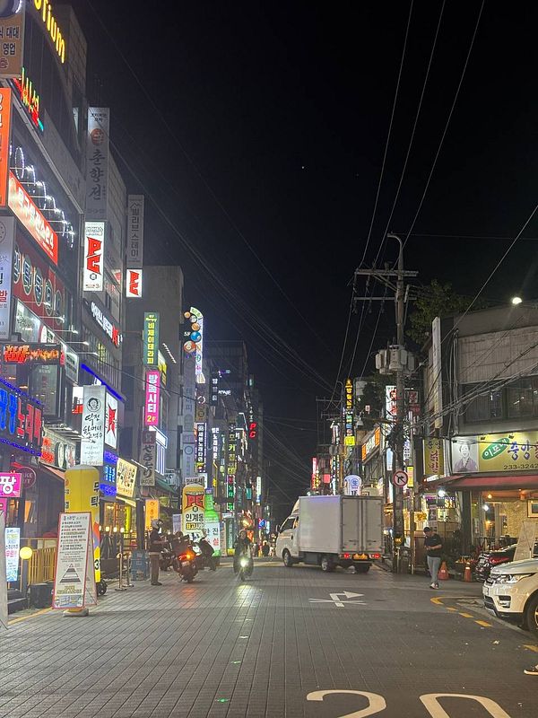 A vibrant street scene at night filled with illuminated signs and activity.