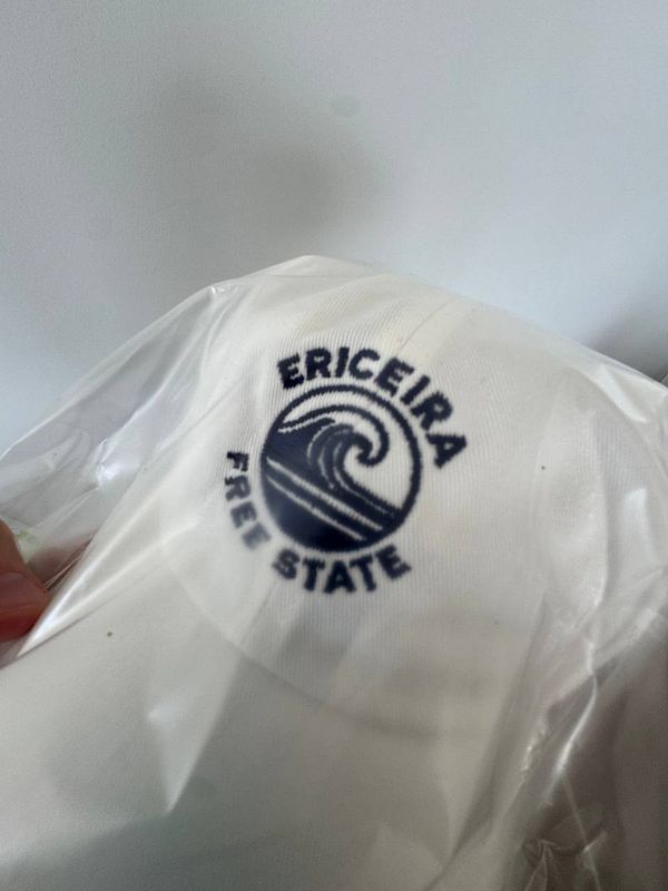 A white cap featuring the 'Ericiera Free State' logo is partially visible in a plastic wrapping.