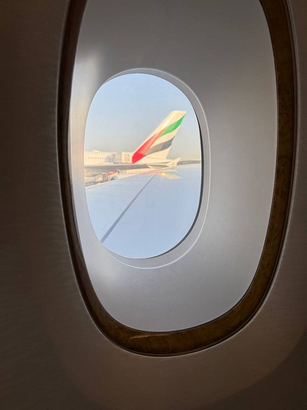 A view from an airplane window showing the wing of an Emirates aircraft.