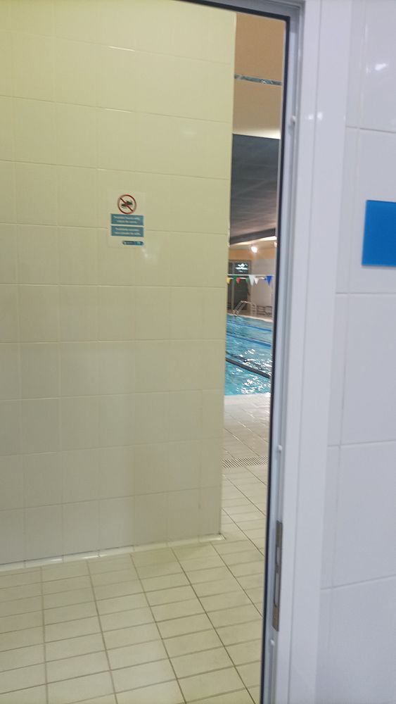 A man running on a paved path adjacent to a green hilly landscape under a partly cloudy sky.