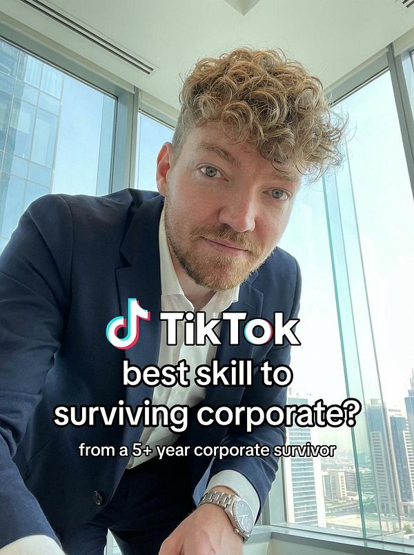 A man in a suit poses in an office setting, promoting a TikTok theme about corporate survival skills.