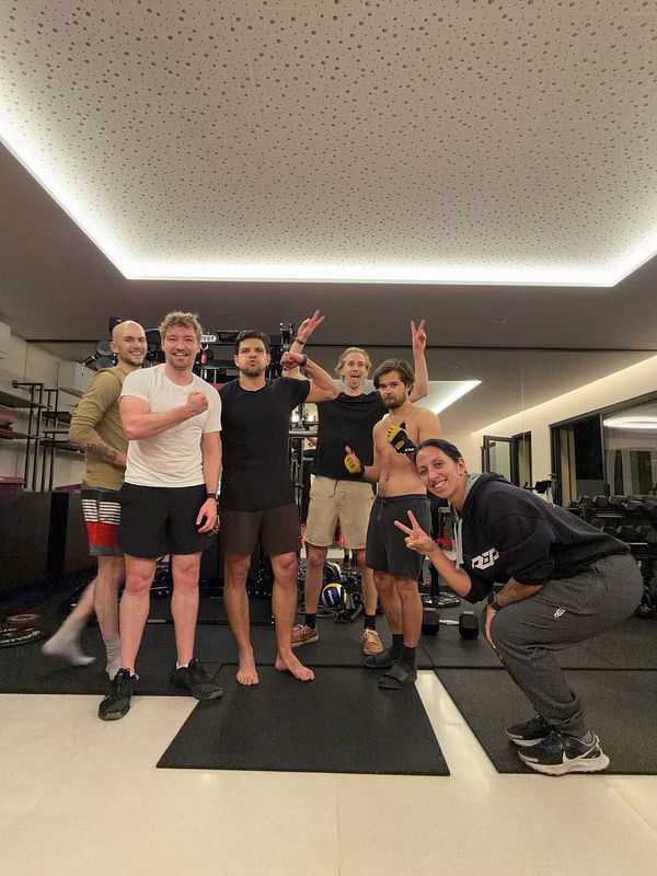 A group workout session in a home gym featuring two individuals exercising together.