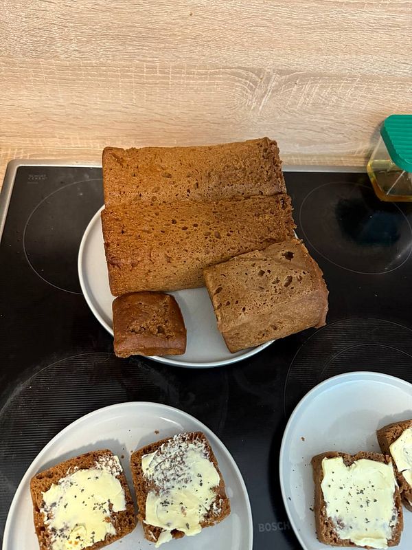 The image features freshly baked Icelandic Rugbrauð, a sweet rye bread, displayed on plates with butter spread.