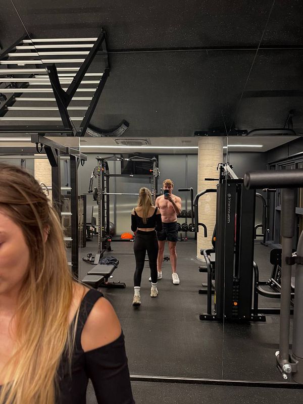 A gym selfie featuring two individuals in a modern fitness facility.
