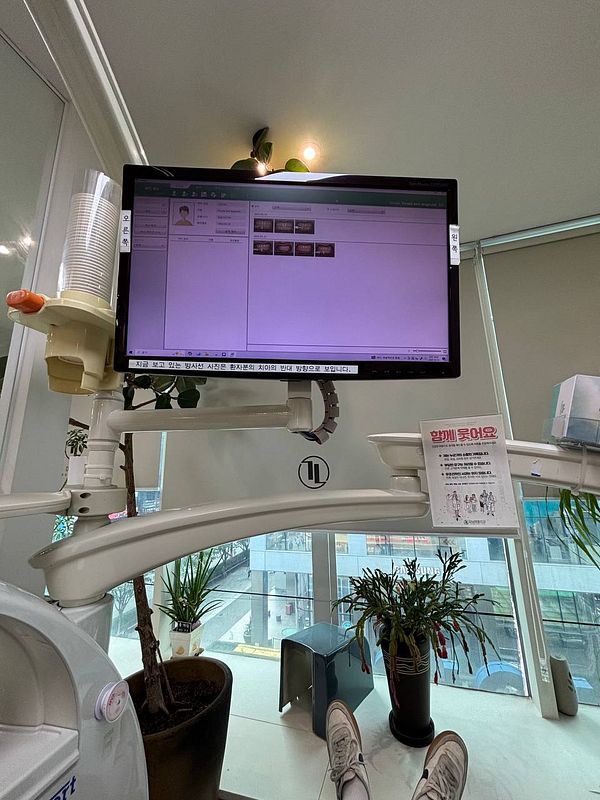 A dental office scene featuring a computer monitor displaying patient information and dental images.