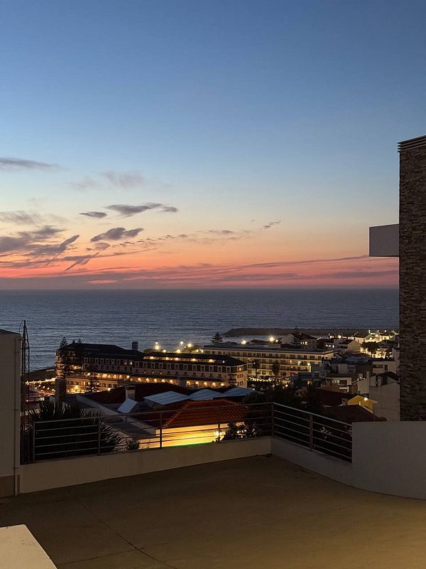 A serene sunset view over the ocean and a coastal town.