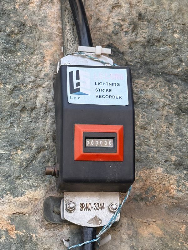 A lightning strike recorder mounted on a rocky surface displays a count of lightning strikes.