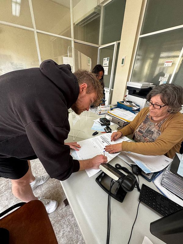 A young man is signing documents at a driving school office.