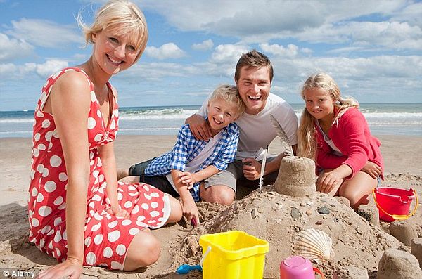 A family enjoys a sunny day at the beach, building a sandcastle together.