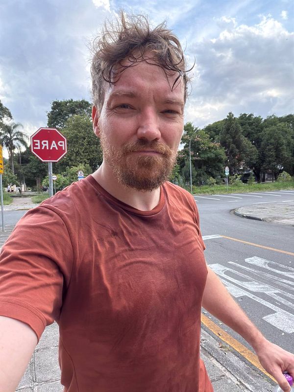 A young woman lifting weights in a gym with a personal trainer assisting her.