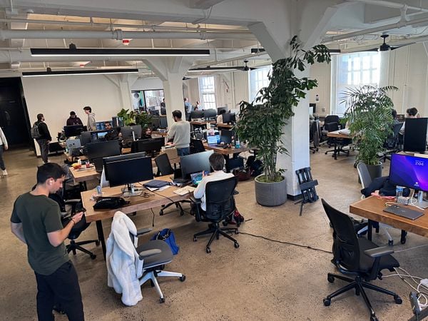 A busy office space filled with people working at desks with computers.