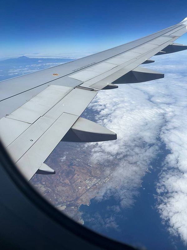 Aerial view from an airplane window showcasing a wing and a landscape below.