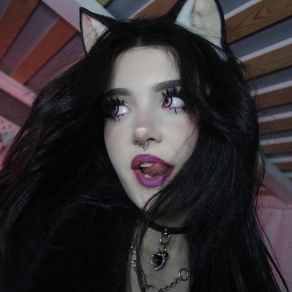 A young woman with cat-like features poses with a playful expression.