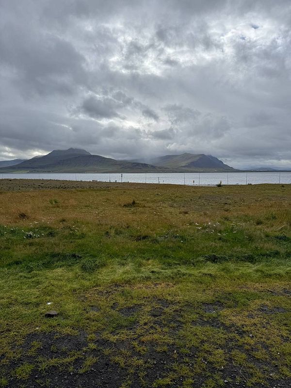 A scenic view of a coastal landscape in Snæfellsnes, Iceland, under a cloudy sky.