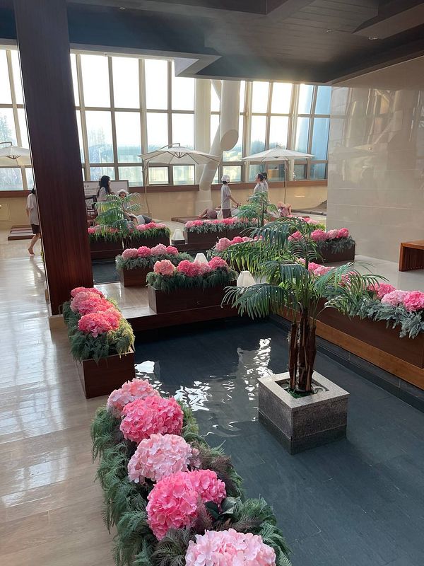 A serene spa environment featuring lush floral arrangements and a tranquil water feature.