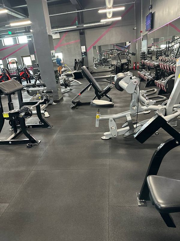 A well-equipped gym interior featuring various workout machines and weights.