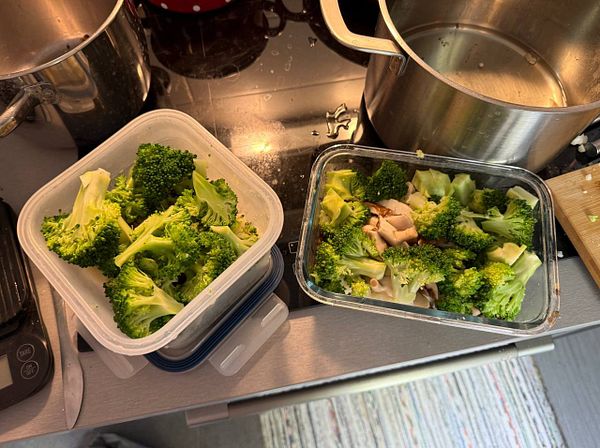 The image features prepared broccoli in two containers on a kitchen countertop.