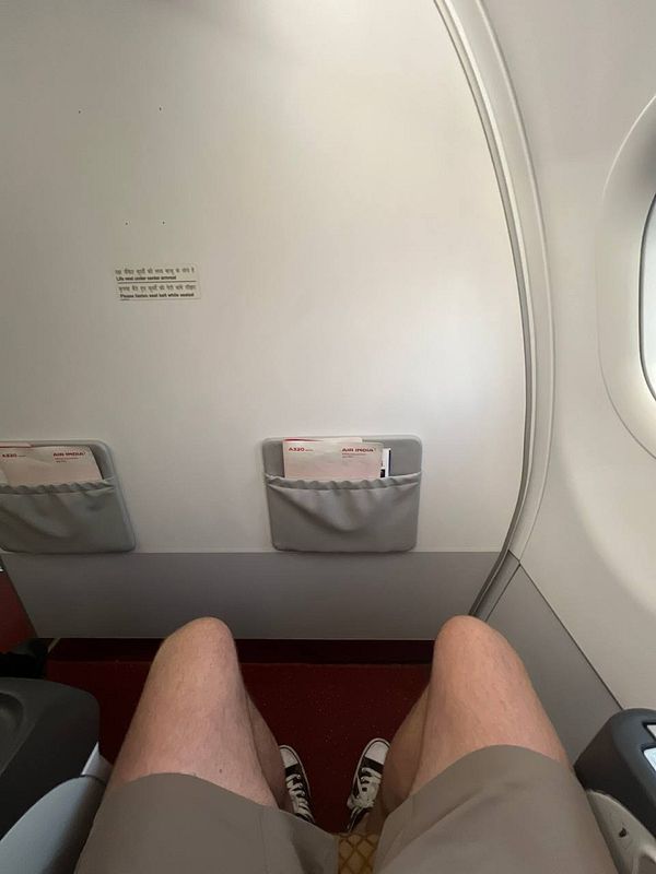 A view from an airplane seat showing a passenger's legs and the cabin interior.