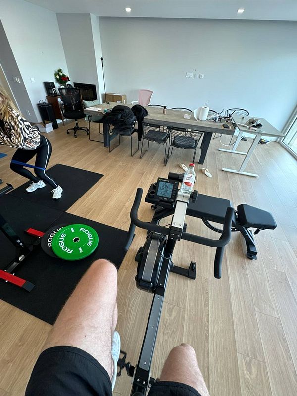 A home gym setup featuring a rowing machine and a person exercising.