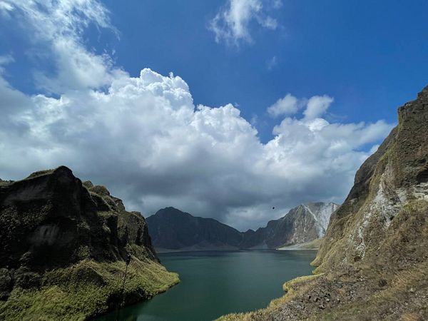 Scenic mountain landscape with a winding trail under a vibrant blue sky with clouds.