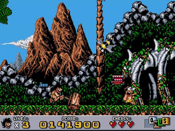 A screenshot from the 1990s platform video game Prehistorik 2 showing a caveman character navigating a prehistoric landscape with mountains, rocks, and dinosaur bones.