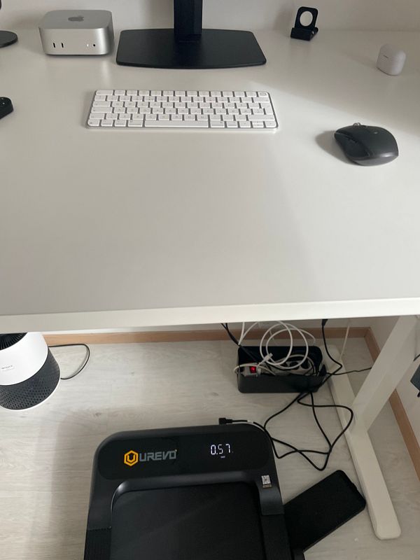 Wooden standing desk equipped with a computer monitor and keyboard, along with a compact treadmill underneath it.