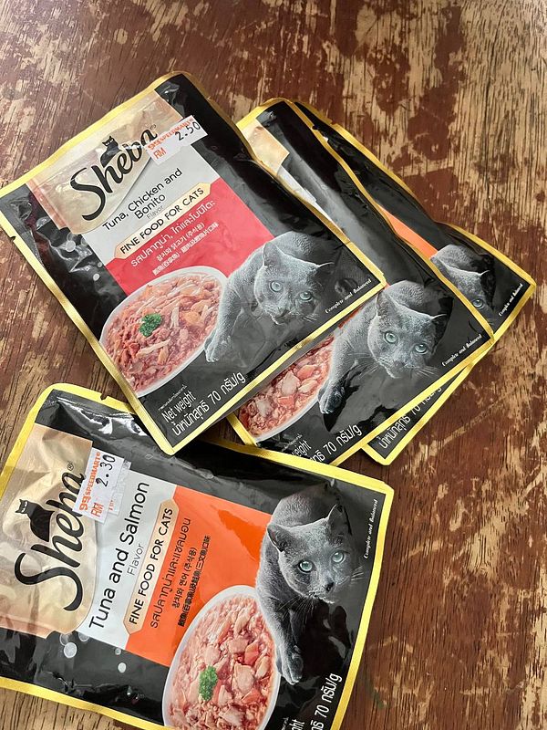 The image features several packets of cat food arranged on a wooden surface.