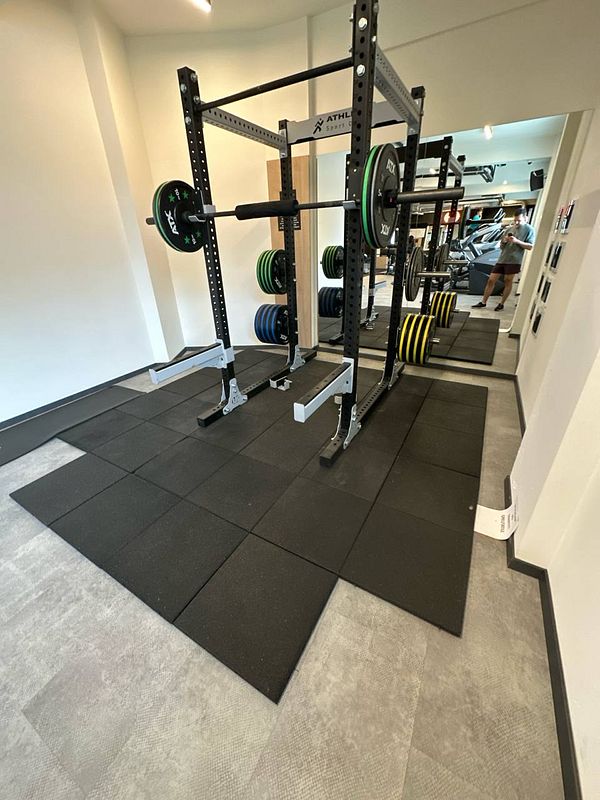 A well-equipped gym area featuring a squat rack and weight plates.