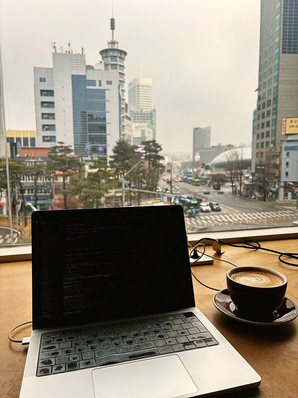 A cozy coworking scene featuring a laptop and a cup of coffee with a city view.