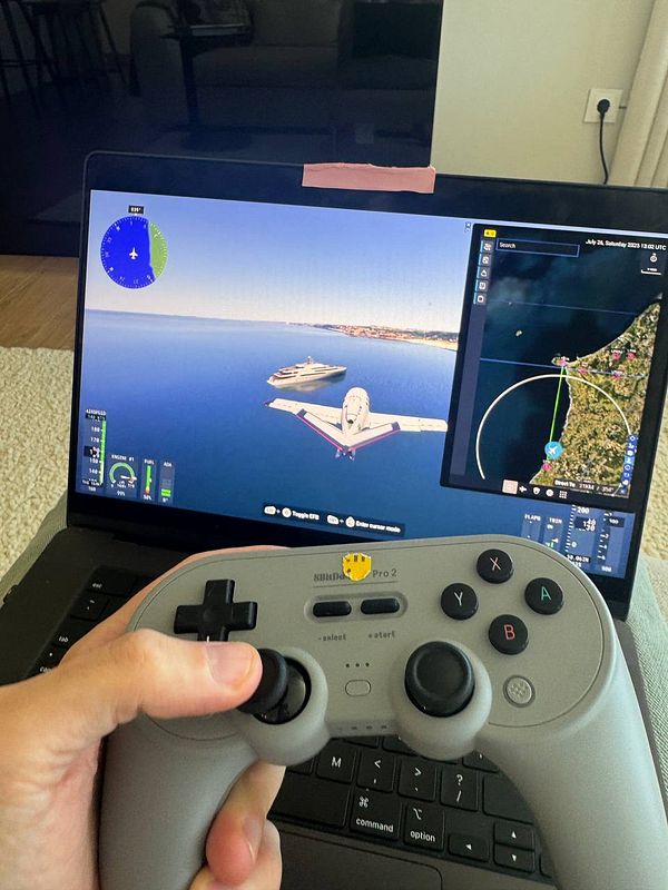 A person is playing a flight simulation game on a laptop using a game controller.