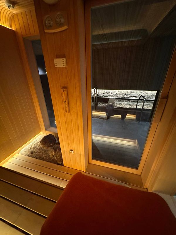 A cozy sauna interior featuring wooden elements and a view of a stone area.