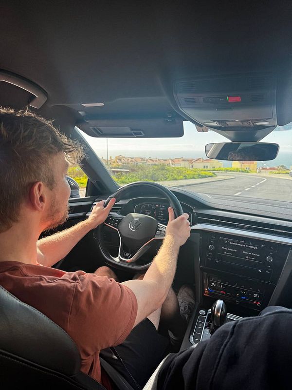 A person is driving a car for the first time in 20 years, gripping the steering wheel with a focused expression.