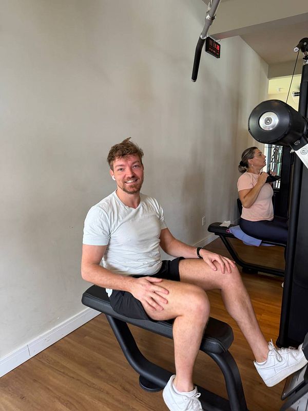 A photo of a man in a gym lifting weights with a mirror reflecting his image.