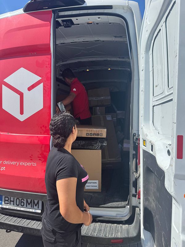 A woman observes a delivery being unloaded from a DPD postal van, which is not suitable for fresh meat delivery.