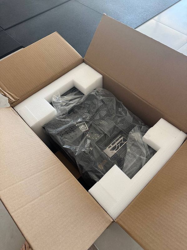 A partially unpacked flight simulation computer is shown in its cardboard box, revealing a CPU cooler that is not fully attached.