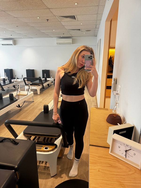 A person is taking a selfie in a modern Pilates studio.