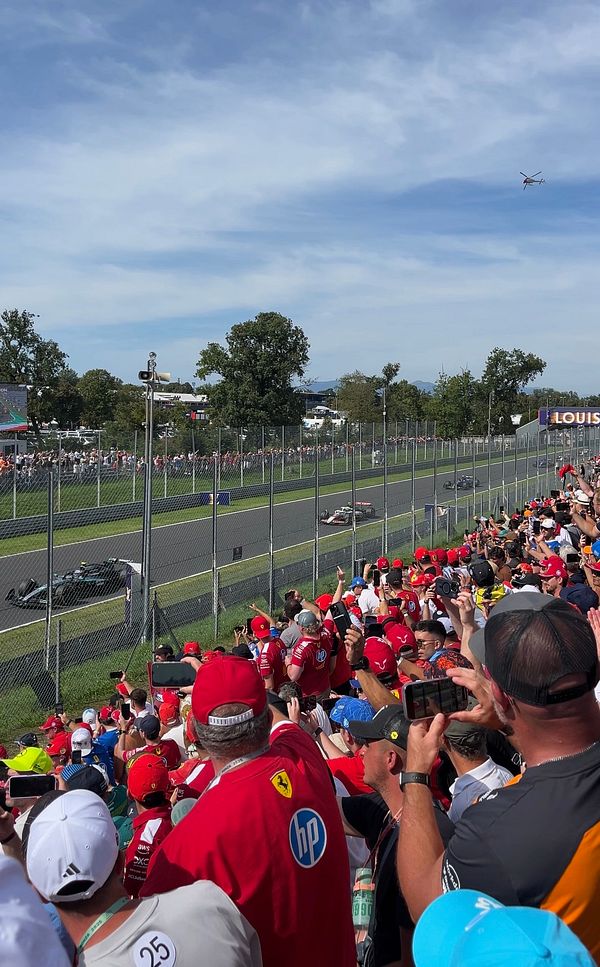 A vibrant scene from the Monza F1 race with a large crowd and racing cars in action.