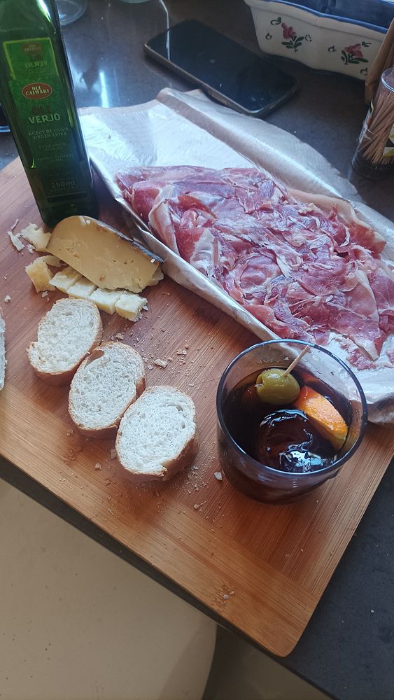 A wooden cutting board is laid out with various food items and a drink.