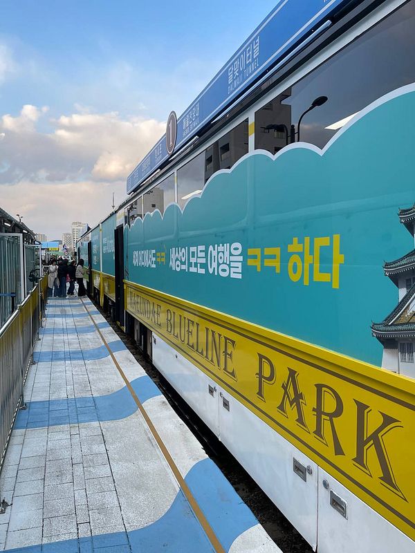 A vibrant seaside train station featuring colorful train cars and a scenic walkway.