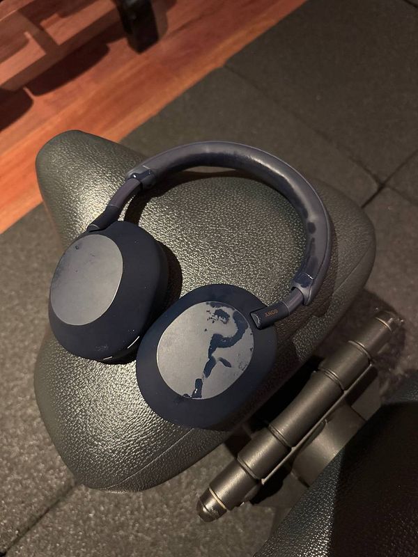 A pair of navy blue headphones rests on a gym bench.